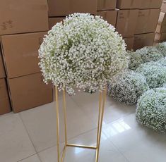 a bunch of flowers that are sitting in a vase on a stand next to boxes