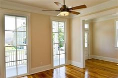 an empty living room with hard wood flooring and ceiling fan in the middle of the room