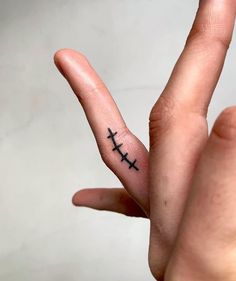 a person's finger with two crosses tattooed on it