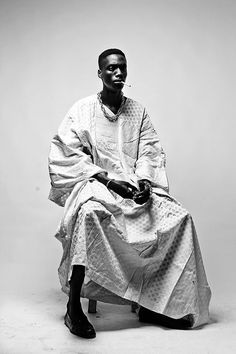 a man sitting on top of a chair wearing a white dress