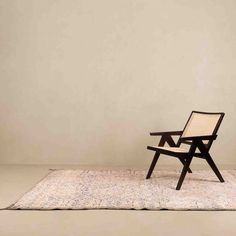 a chair sitting on top of a rug in front of a white wall and floor