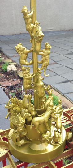 a gold colored clock tower with animals on it's sides and four candles in the middle