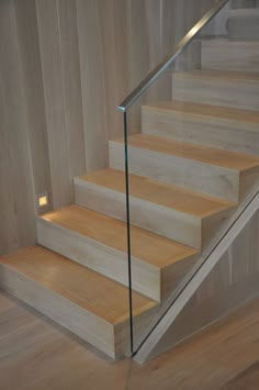 a wooden stair case with glass handrails