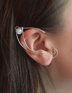 a woman's ear is shown with an ear cuff in the shape of a spiral