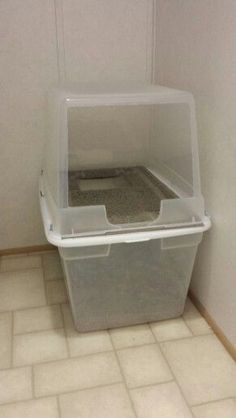 a plastic container sitting in the corner of a room with tile flooring and white walls