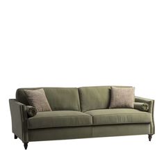 a green couch with two pillows on it's back and one arm facing the camera