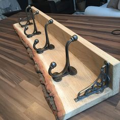 three wrought iron hooks on a wooden tray