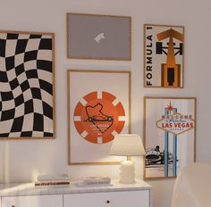 a room with posters on the wall and a white dresser in front of it that has a lamp next to it