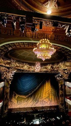 an ornately decorated stage with chandelier and curtained seats in the center