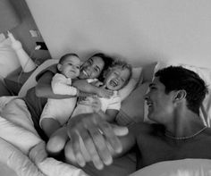 a man and woman are laying in bed with their babies