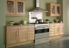 a stove top oven sitting inside of a kitchen next to wooden cupboards and drawers