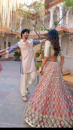 a man and woman dancing together in front of a building with flowers hanging from the ceiling