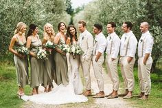 a group of people standing next to each other in front of an olive tree filled field