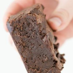 a hand holding a piece of brownie in it's left hand with chocolate chips on top