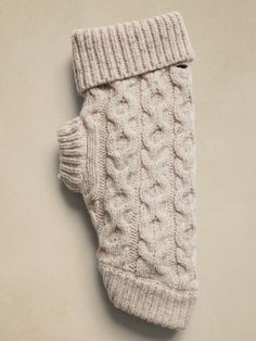 a white knitted mitten laying on top of a beige surface with one hand in it's pocket