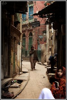 a man walking down a street next to people on the other side of an alley