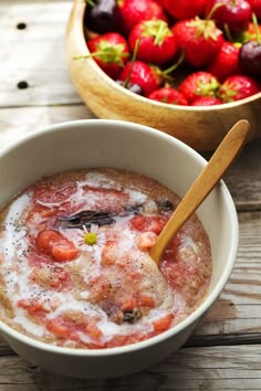 a bowl of food with strawberries in it and a wooden spoon next to the bowl