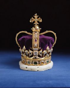 a gold crown with jewels on it sitting on top of a blue cloth covered table