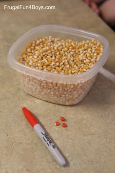 a plastic container filled with corn next to a marker on a counter top and a person in the background