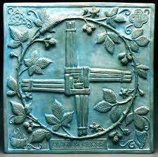 a metal plaque with leaves and crosses on it's sides, in the shape of a cross