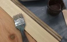 a paintbrush sitting on top of a wooden table next to some wood planks