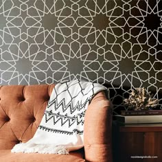 a brown couch sitting in front of a wall with geometric designs on the back and sides