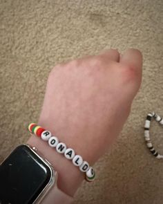 a person wearing a bracelet with the word canada on it next to a cell phone