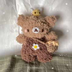 two brown teddy bears sitting next to each other on a white bed sheet, one has a yellow flower in it's mouth