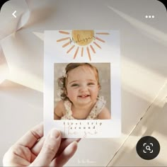 a hand holding up a card with an image of a smiling baby in the center