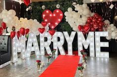 a red carpet is on the floor in front of balloons and letters that read marry me