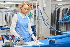 a woman ironing clothes in a factory with a blue table cloth on the floor