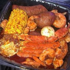 a plastic container filled with seafood and corn on the cob