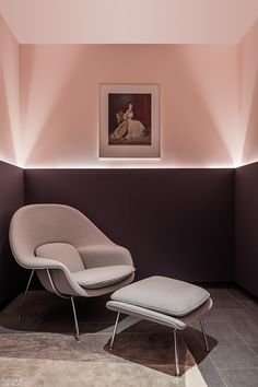 an egg chair and ottoman in a room with pink lighting on the wall behind it