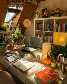 a desk with a laptop, books and other items on it in front of a window