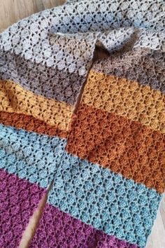 a multicolored crocheted blanket laying on top of a wooden floor