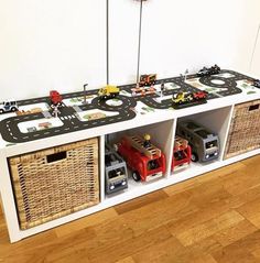 toy cars and trucks sit on top of a white shelf with wicker bins