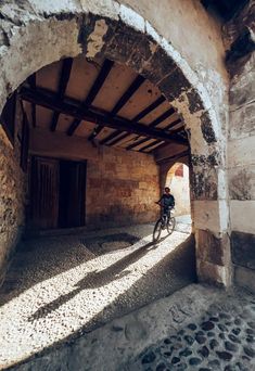 a person riding a bike in an old building with stone walls and arched doorways