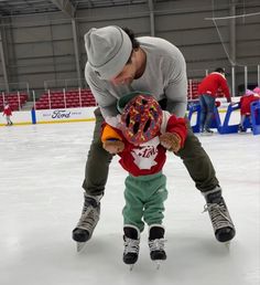 a man is teaching a child how to skate on an ice rink with skis