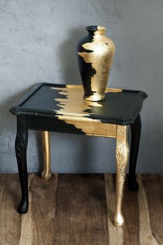 a black and gold table with a vase on top