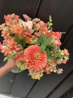 a person holding a bouquet of flowers in front of a ceiling fixture with black walls