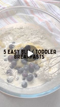 a bowl filled with batter and blueberries on top of a table