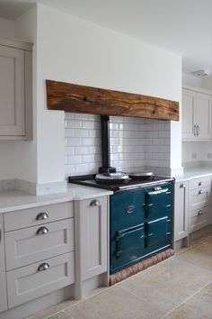 a stove top oven sitting inside of a kitchen next to white cupboards and drawers