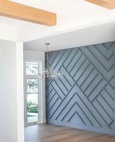 an empty room with wood flooring and blue wall paneling in the center, next to a chandelier