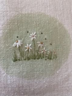 some white daisies are in the grass on a linen background with small black dots