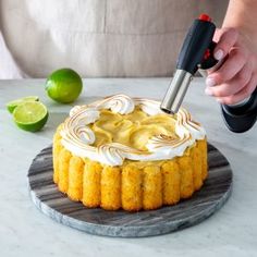 a person is decorating a cake with icing and limes on the table