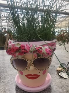 a potted plant with sunglasses and flowers on it's head is sitting on a table