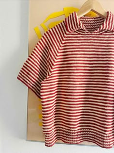 a red and white striped shirt hanging on a hanger next to a yellow object