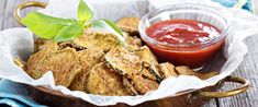 some fried food is sitting in a bowl with ketchup and sauce on the side