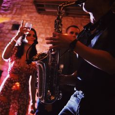 a man playing the saxophone while two women look on