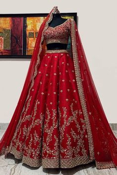 a red bridal gown on display in front of a painting